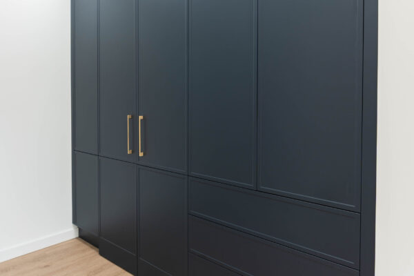 Wall of cabinetry in a dark finish and gold handles on display in our Glandore U-Install-It Kitchens Showroom
