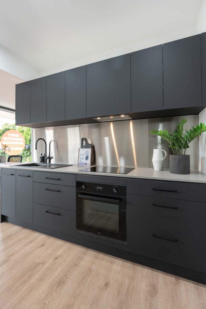 Image of black supermatte kitchen with haier undermount rangehood, black Oliveri sink and tap, haier oven, and stone benchtop.