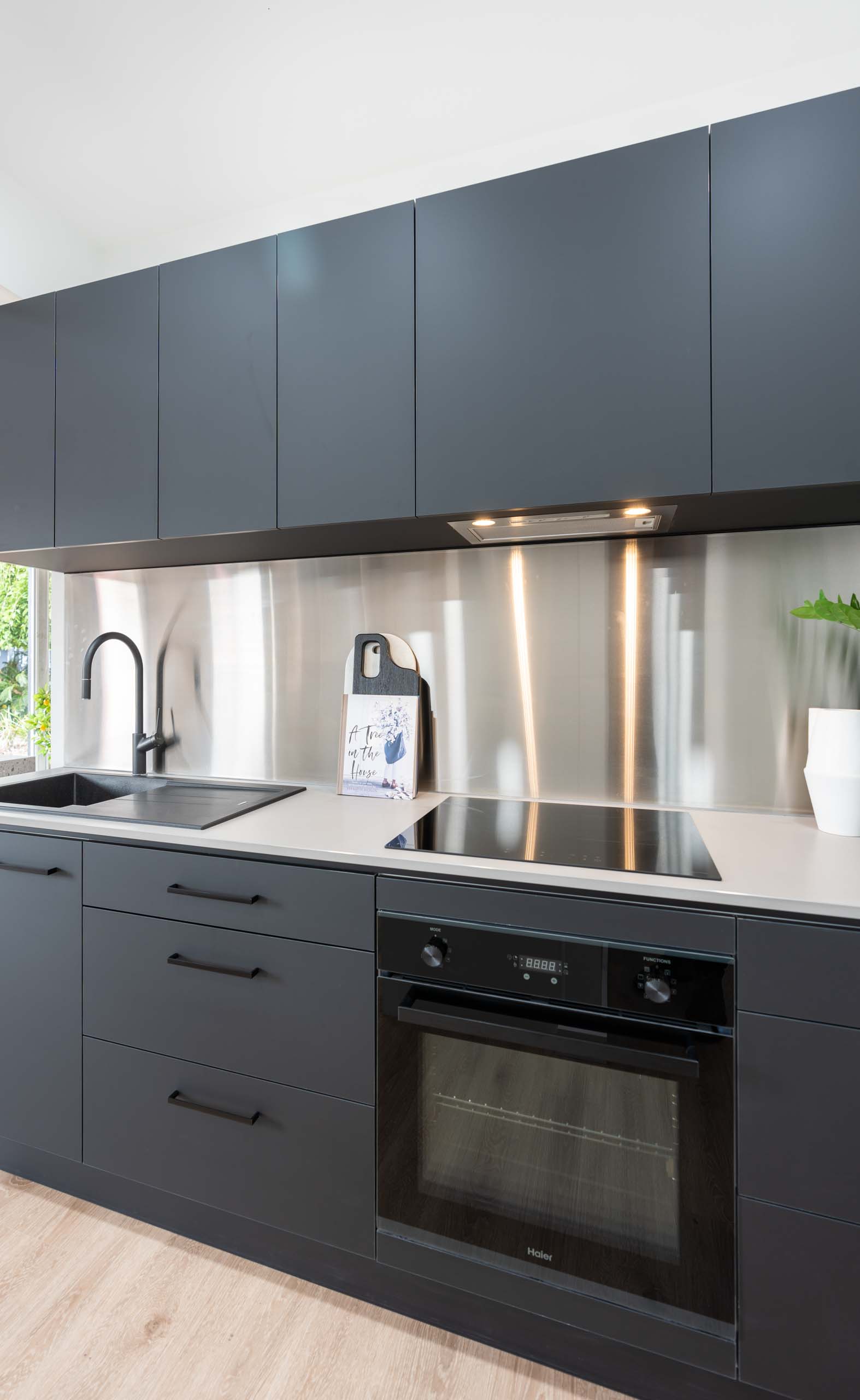 Image of black supermatte kitchen display with black kitchen appliances and stainless steel splashback