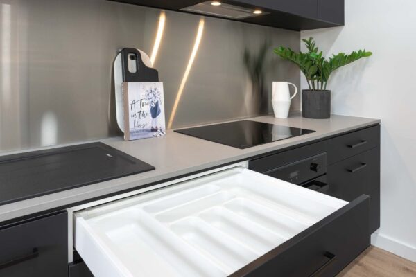 Black Kitchen with stainless steel splashback. Drawer unit showcasing the in built cutlery tray