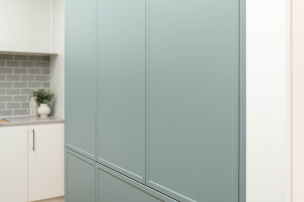 Two tone kitchen, white and sage green cabinetry. Push to open cabinets, with a shaker profile doors.