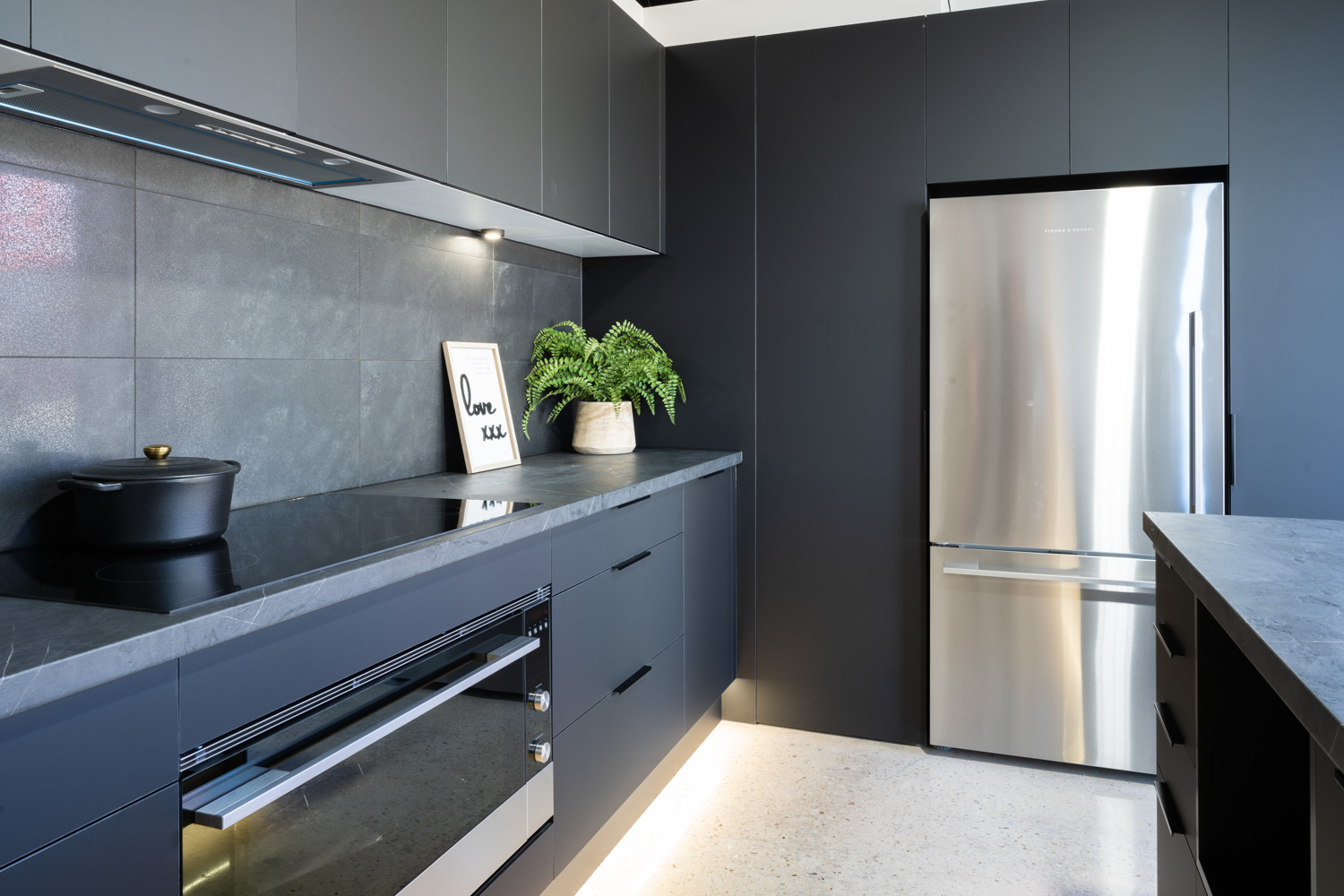 Black Touch kitchen with a dark veined laminate benchtop. Fisher & Paykel bottom mount fridge