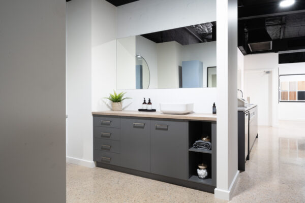 Bathroom vanity with above the counter basin, timber look benchtop, grey cabinetry and a feature open shelves display.